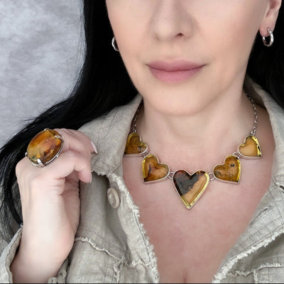 Woman wearing a necklace with heart-shaped pendants against a neutral background